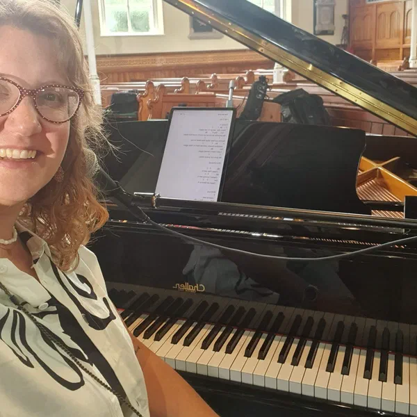 Sarah beside a grand piano in a church setting