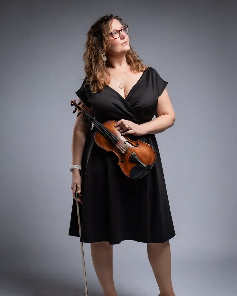Sarah Ballard in a black dress holding her violin and bow